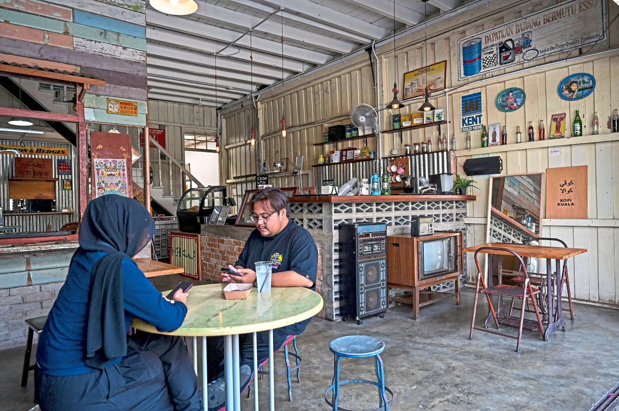 Visitors enjoying the nostalgic atmosphere of a traditional wooden shophouse in Kuala Dungun.