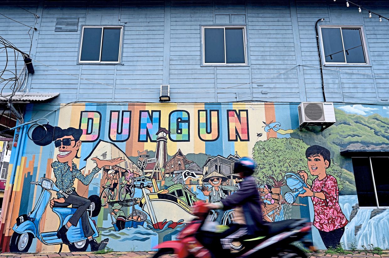 A mural depicting scenes from everyday life adorns a wooden shophouse.
