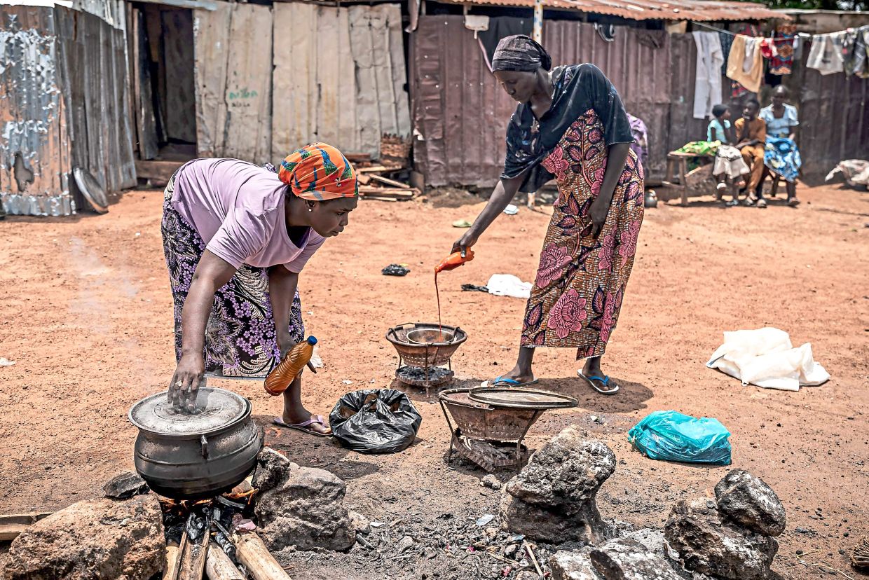 Hawa (right) cooking at an internally displaced persons camp in Durumi. — AFP