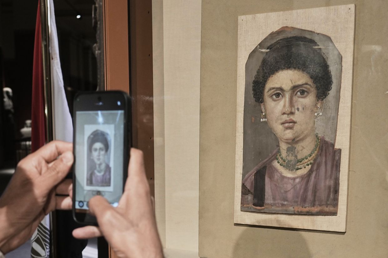 A visitor films one of Fayoum portraits 'Demos', from the Greco-Roman period the 1st century BC, at the Egyptian Museum in Cairo, Egypt. Photo: AP