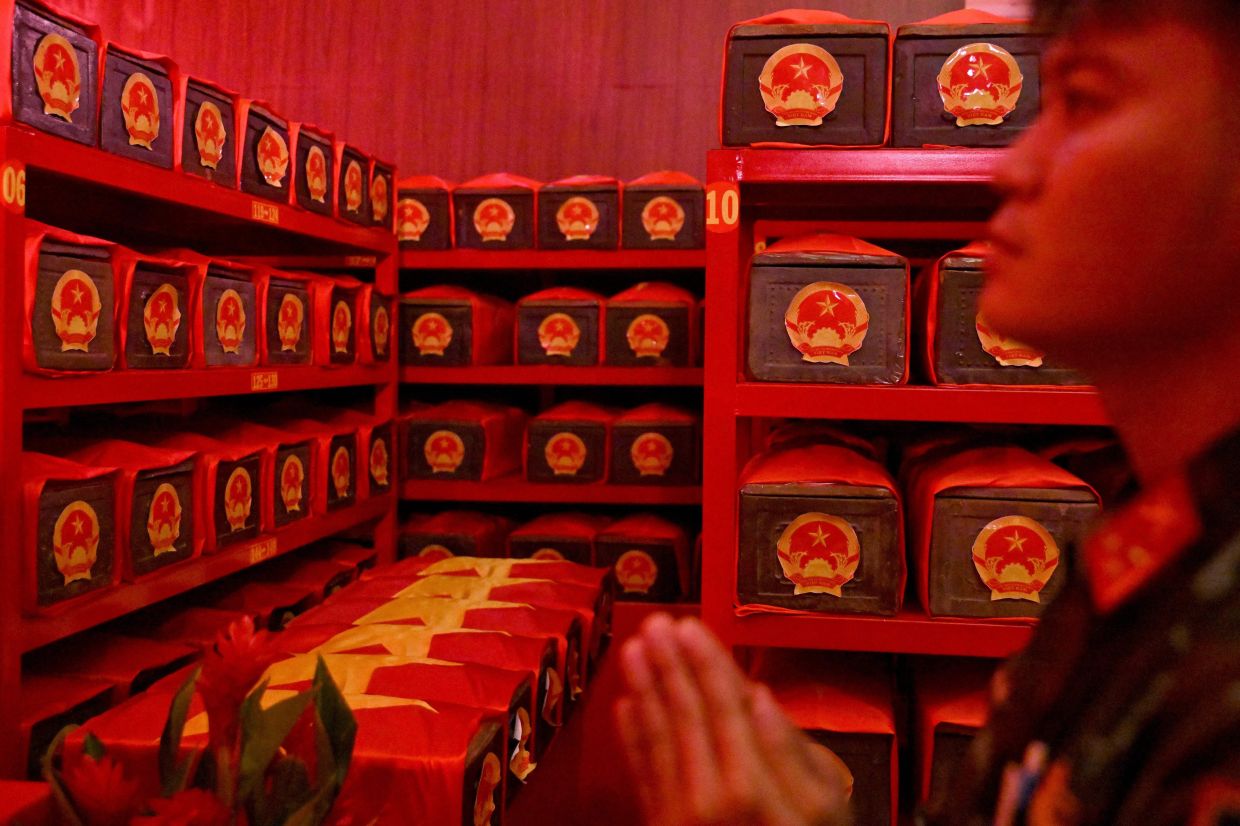 A soldier stands in prayer inside a holding room housing the remains of fallen soldiers at Le Thi Rieng Park in Ho Chi Minh City on Oct 13, 2026. Vietnam held funeral rites for more than 700 of its war dead on Oct 14, unearthed in a major push to identify those missing from decades of conflict with France and the United States. - Photo: AFP