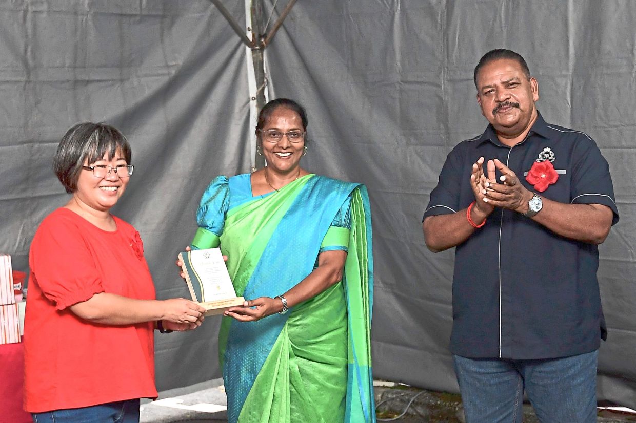 Parimala receiving RM3,000 from Hew. With them is DSP Sivakumar.