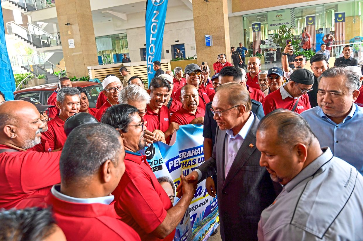 Pleasure to meet you: Anwar shaking hands with taxi drivers as Loke (right) looks on. — EZARD FAROUQ/The Star