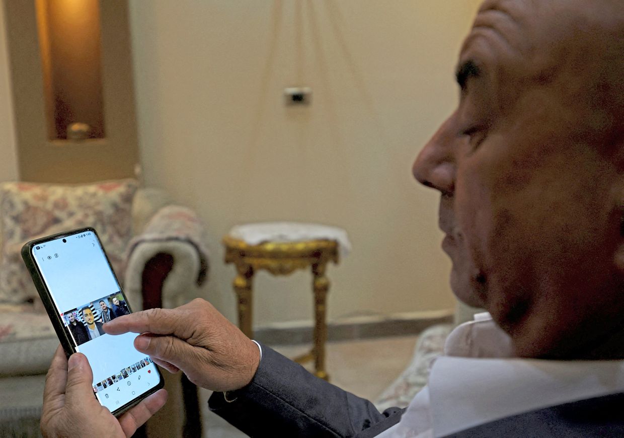 Hassayna looking at photos of his four sons who were killed by Israeli airstrikes. — Reuters