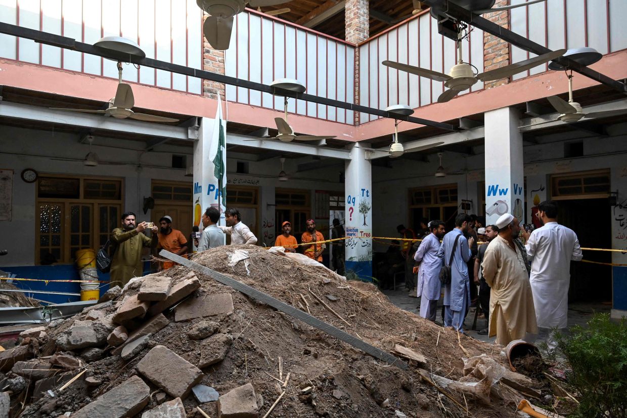People gather around debris and rubble lying in the courtyard of a school following a roof collapse, in Peshawar on October 15, 2026. The roof of a school collapsed in Pakistan's northwestern city of Peshawar, killing a teacher and 32 students, mostly aged under 14, health officials said on October 15, as residents and rescuers scrambled to pull children from the rubble. - Photo: AFP
