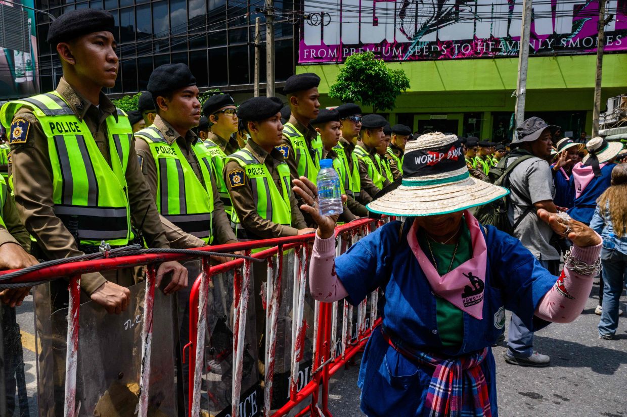 Demonstrators dance in front of a line of police standing guard during a protest against the International Monetary Fund (IMF) and World Bank Group in Bangkok on Friday, October 16, 2026, as the IMF Annual Meetings take place in the Thai capital. -- Photo by ANTHONY WALLACE / AFP