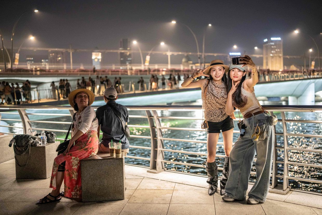 People take photographs at Merlion Park in Singapore on Friday, October 16, 2026, as the country continues to be shrouded in haze caused by fires in Indonesia. Toxic haze has covered parts of Indonesia, Malaysia, and Singapore for weeks as Jakarta struggles to contain fires that have scorched large tracts of Borneo and Sumatra, with the smoke drifting across the region. -- Photo by Yuichi YAMAZAKI / AFP