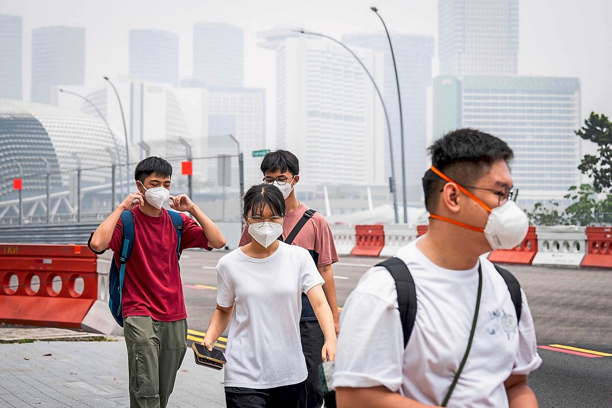 People wearing face masks as they walk along a street in Singapore.
