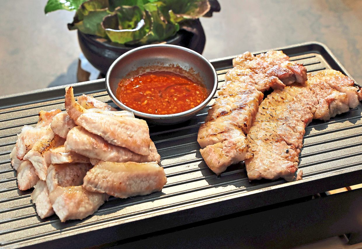 Delicious charcoal-grilled pork options like hanjungsal (pork jowl; left) and samgyeopsal (pork belly; right) are some of the specialties on the barbecue menu.