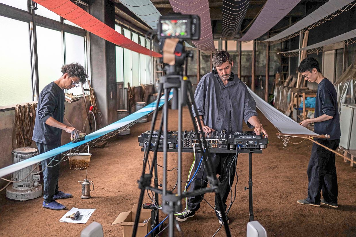 DJ Bonobo (centre) performs a set as part of the Login.jp project as employees dye fabric at the Fujiya Somekobo fabric-dyeing workshop in Tokyo.