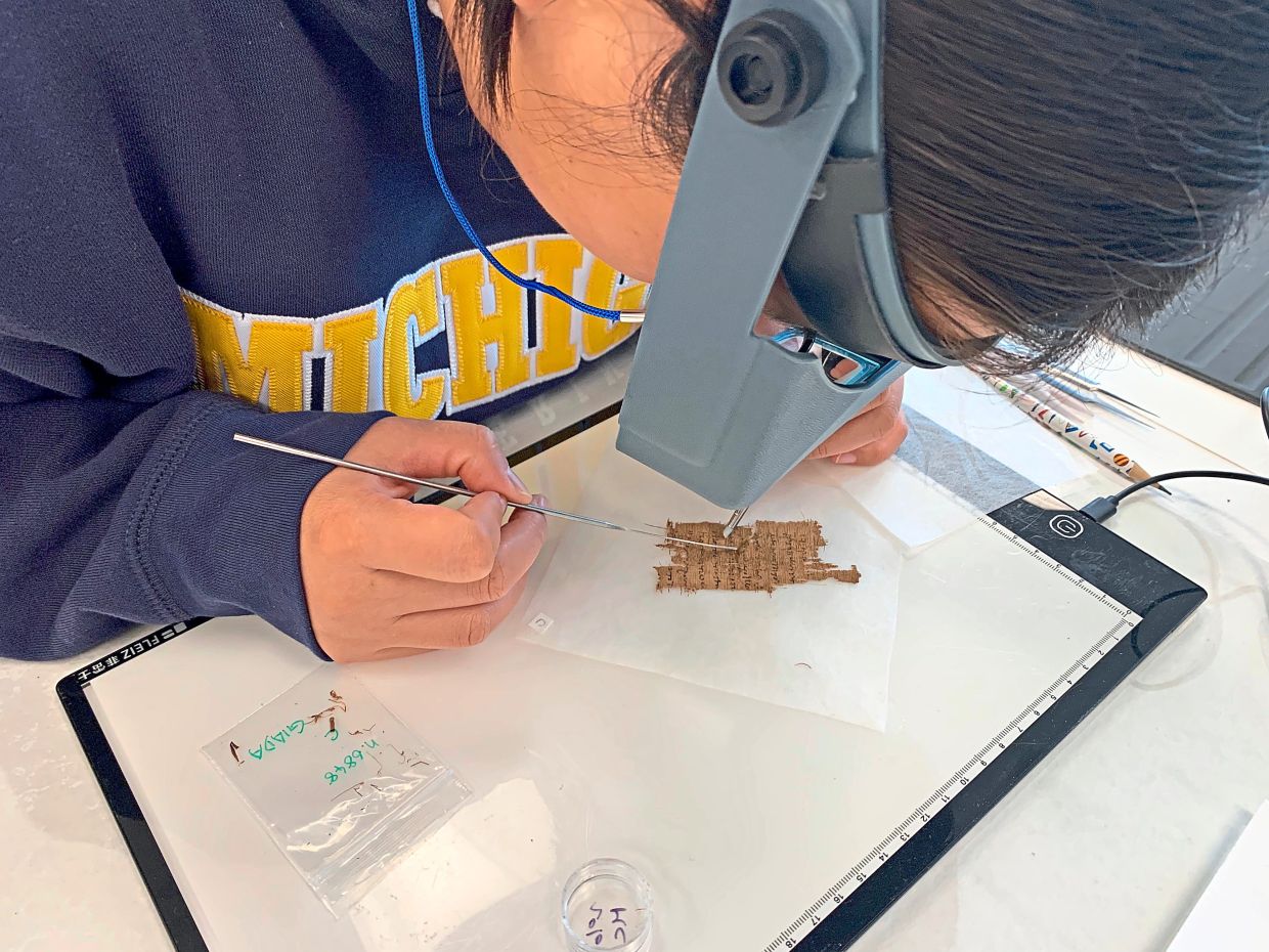 Jiang examines a papyrus fragment at the University of Michigan.