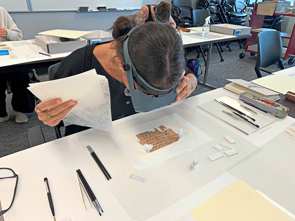 Papyrus Conservation Summer Seminar student Alessandra Quadrelli examines a papyrus fragment at the University of Michigan.