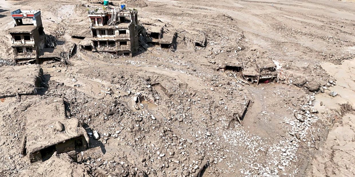 Damaged buildings and infrastructure along the swollen Trishuli River following the massive flash flood.
