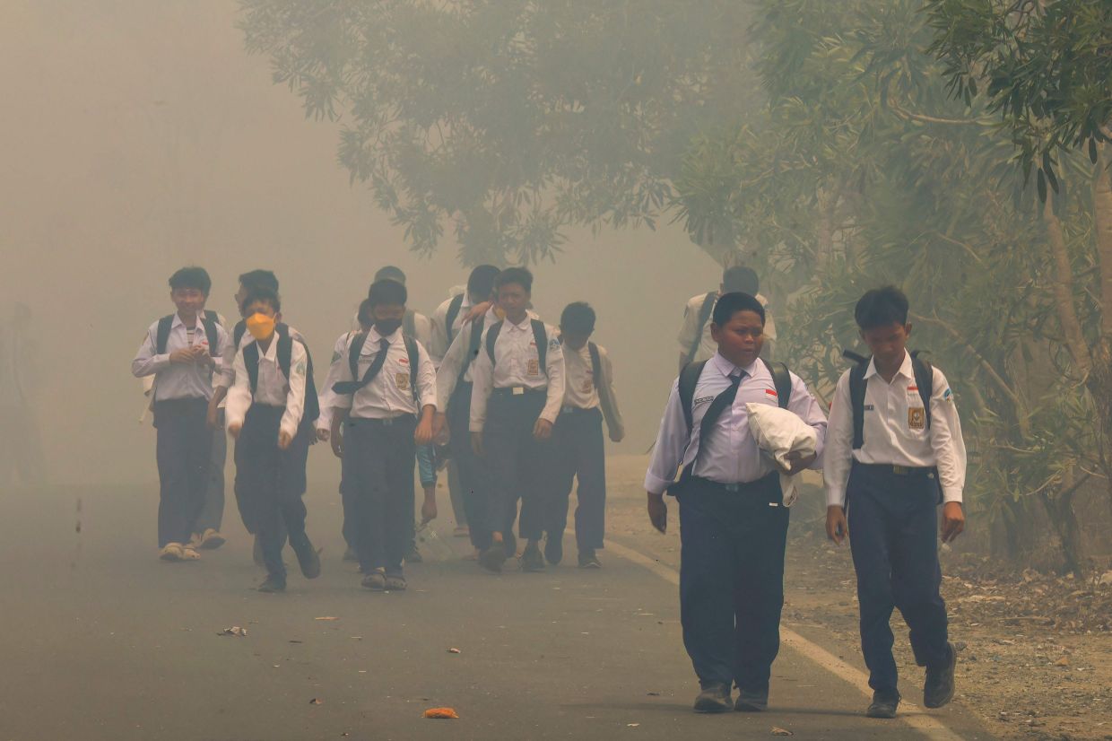 Schoolchildren walk along a smoke-shrouded road in Tegal Arum, Banjarbaru, South Kalimantan, on Oct 20, 2026, as massive forest and land fires blanket the area in thick haze. Indonesian wildfires that have caused a regional haze crisis burned more than 1.9 million hectares in the first nine months of 2026, a monitor analysing satellite data said on Oct 19. - Photo: AFP