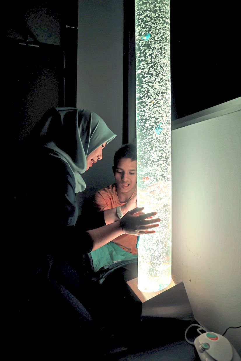 The gentle movement of bubbles and soft lighting can help calm Harith Rafael (right) by reducing anxiety and sensory overload.