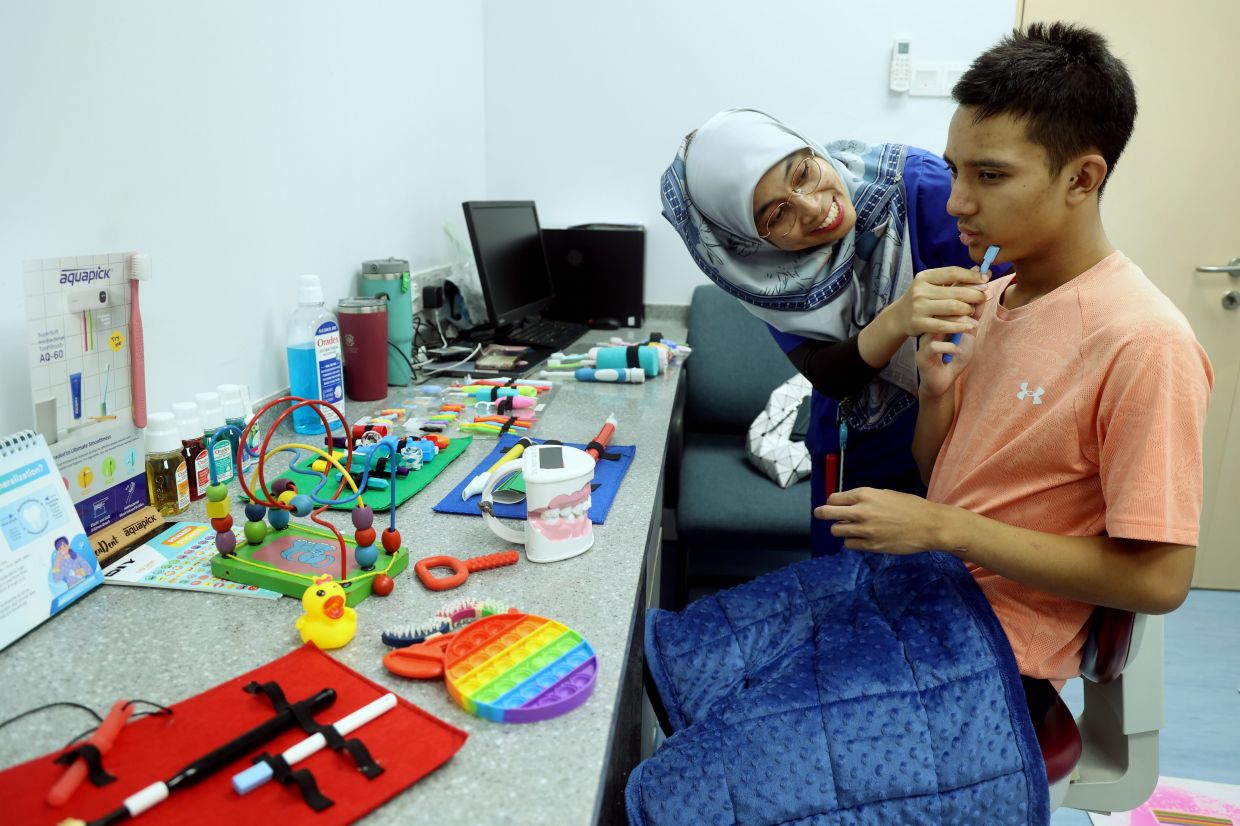 Dr Syafiqah Aina Suhardia patiently attends to Harith Rafael, taking time to help him feel comfortable during his dental visit.