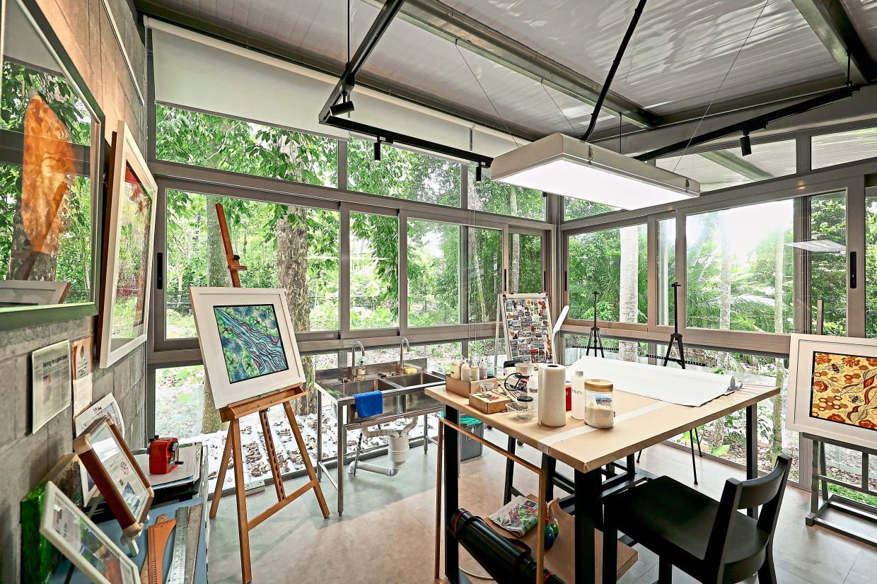 The studio is surrounded by glass panels which overlook the forest.