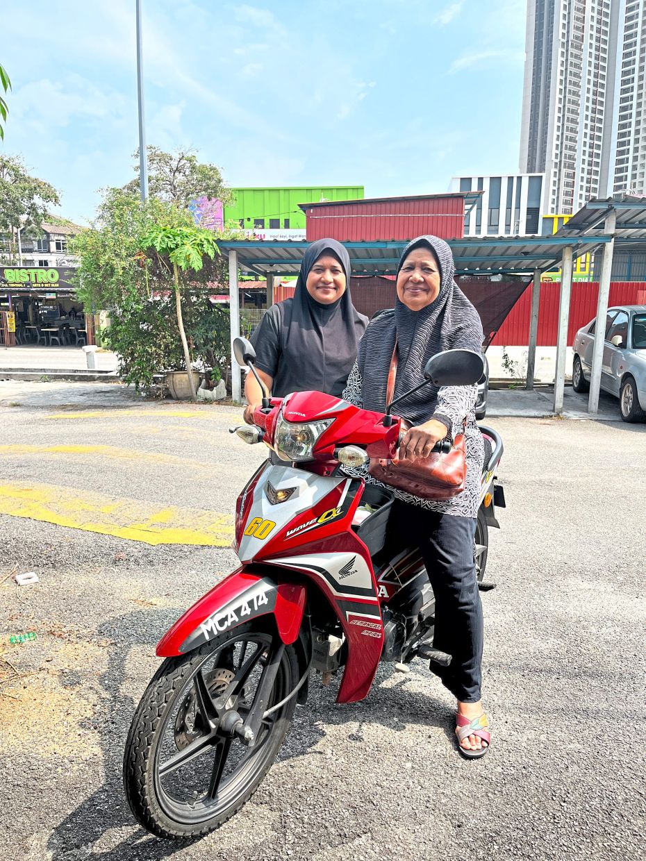 Noridah (right), seen here with her daughter, Marzaina, is aware that she may not be able to ride her motorbike forever. For now, she’s glad for the independence it allows her. Photo: Marziana Mansor