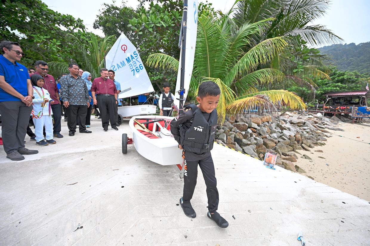 A young sailor from SK Mukut walks down the refurbished slipway with his Optimist dinghy in tow.