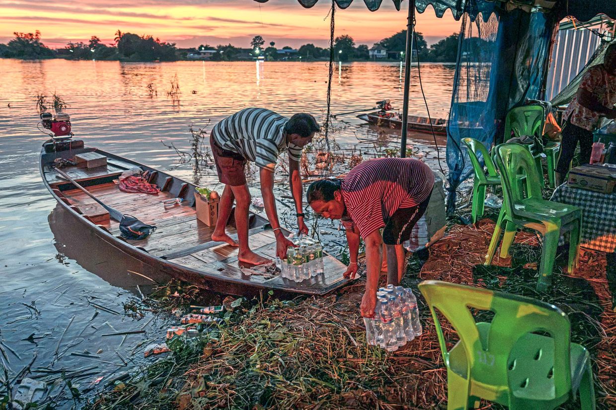 Villagers loading their boat with relief supplies including drinking water in Bang Ban district in Ayutthaya. — AFP
