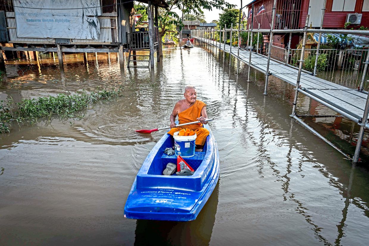 Submerged streets: A Buddhist monk paddling a boat through a flooded neighbourhood in Ayutthaya. — AFP