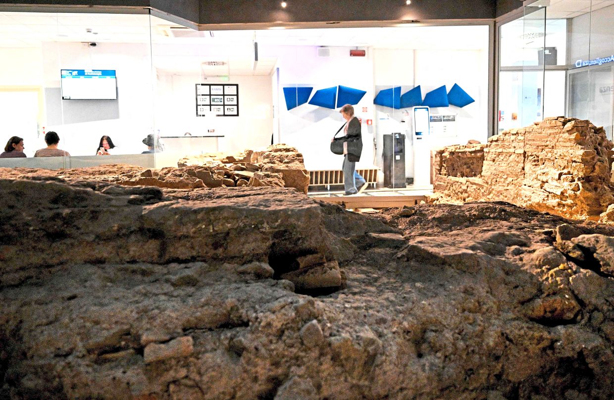 The waiting room inside the hospital's Radiotherapy Department is located right next to the archaeological remains of an ancient Roman temple, offering patients a contemplative view before their oncology treatments.