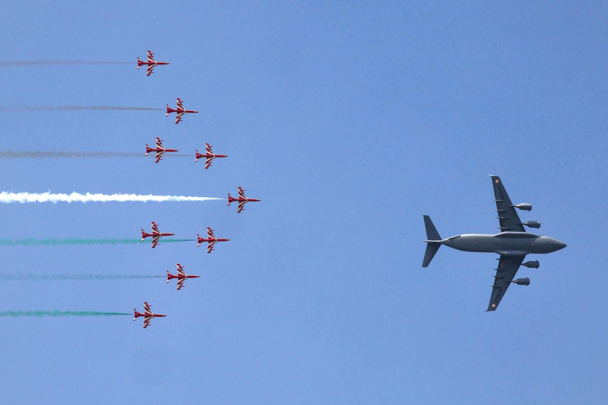 The 'Dashashwa' formation, led by an Indian Air Force (IAF) C-17 Globemaster and a nine-aircraft Surya Kiran Aerobatic Team (SKAT) formation, is seen during the Wings Over Ganges air show over the River Ganges in Varanasi on October 24, 2026. -- Photo by Niharika KULKARNI / AFP