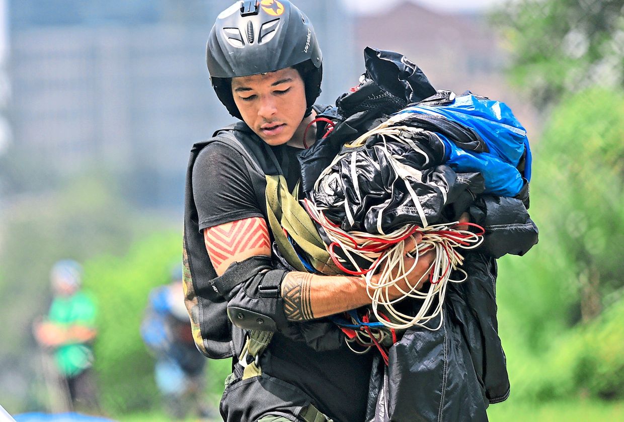 A BASE jumper gathering his parachute after landing on the ground.