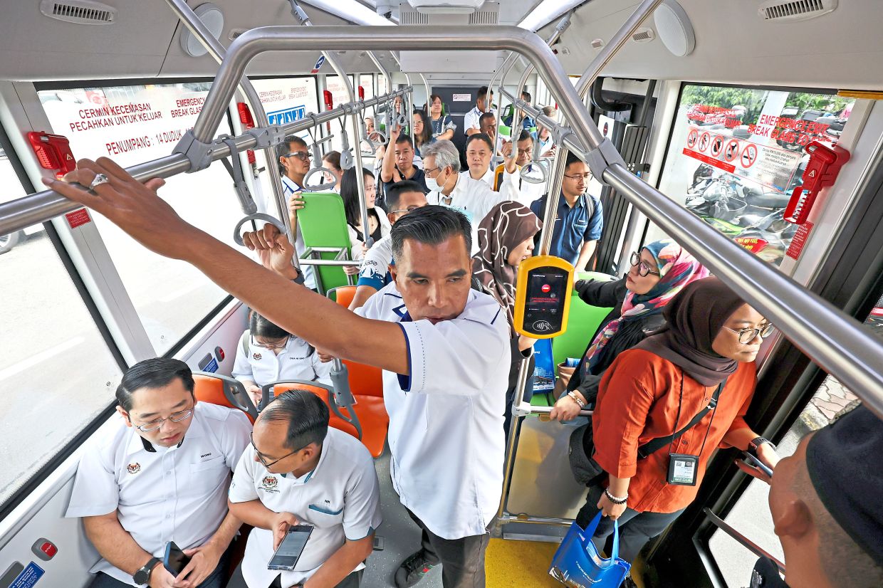Passengers, officials and media personnel taking a ride in one of the new EV buses during a demonstration run in Penang.