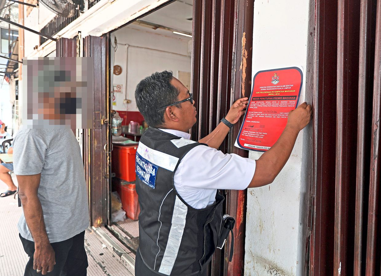 A DBKL officer putting up a closure notice at a food premises during an enforcement operation in Pudu.