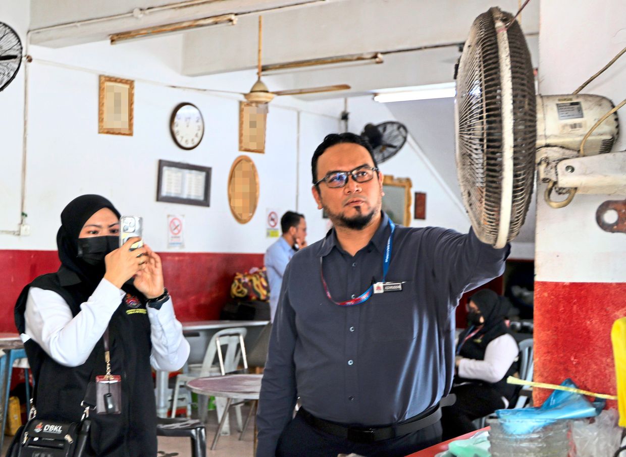 Dr Azaruddin (right) leading the inspection team as he shows a wall fan caked with dust.