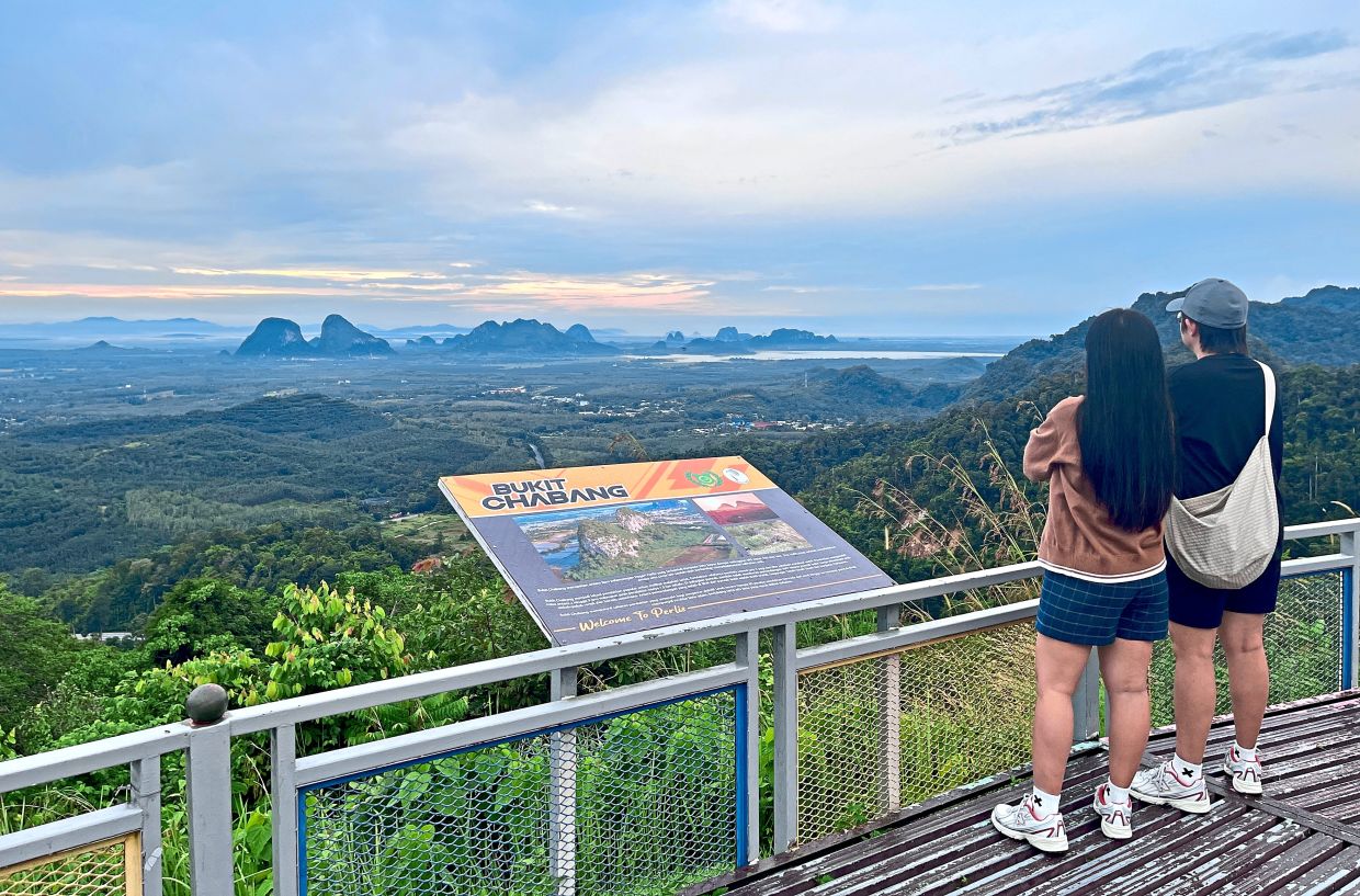 Visitors taking in Bukit Chabang in the distance and the surrounding vista from Wang Kelian Viewpoint.