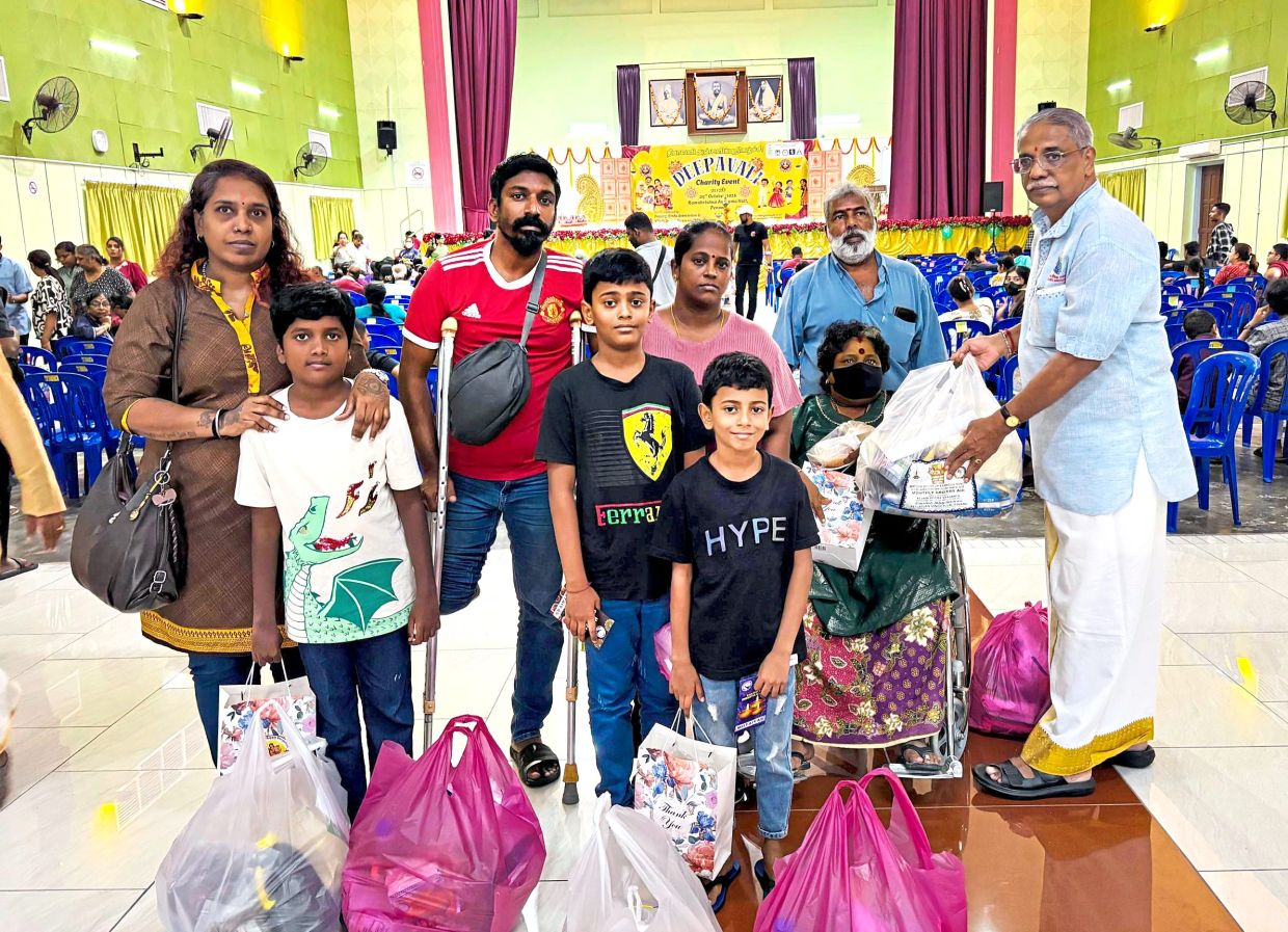Murugiah (right) handing out groceries and goodie bags to recipients during the event. — Handout