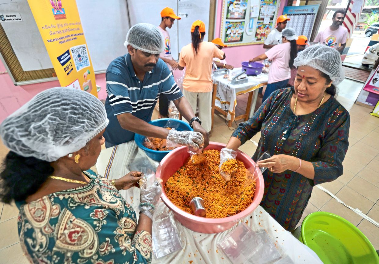 Members of Malaysia Hindudharma Penang Branch and Om Sakhti Devotees Association Penang Branch packing muruku and other traditional cookies at SJKT Azad.