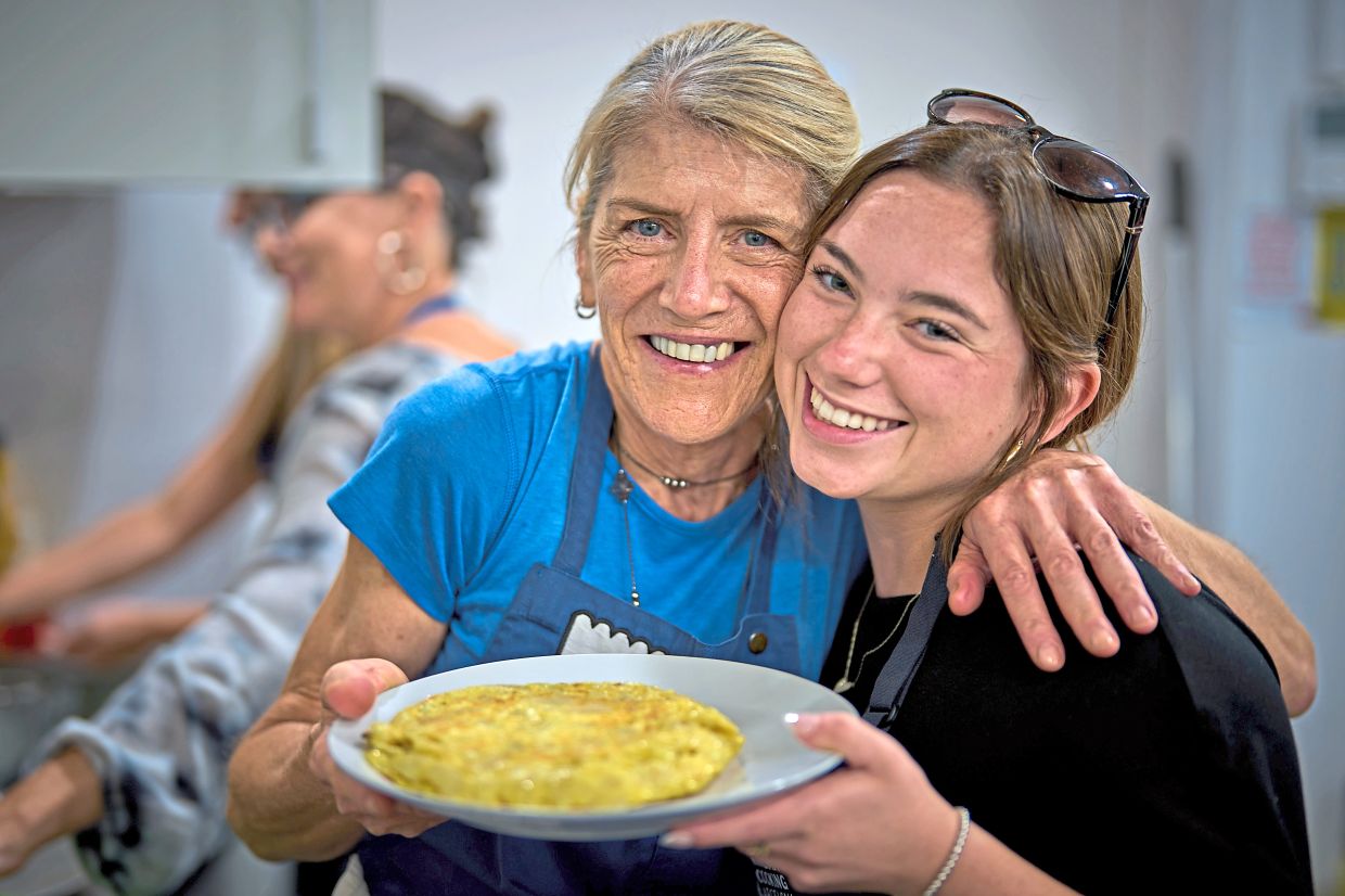 Sonia Castel, 63, left, poses with a tourist after teaching her how to make a traditional Spanish omelet during a cooking workshop at Grandmas Cooking in Barcelona, Spain, Wednesday, Oct. 14, 2026. (AP Photo/Emilio Morenatti)