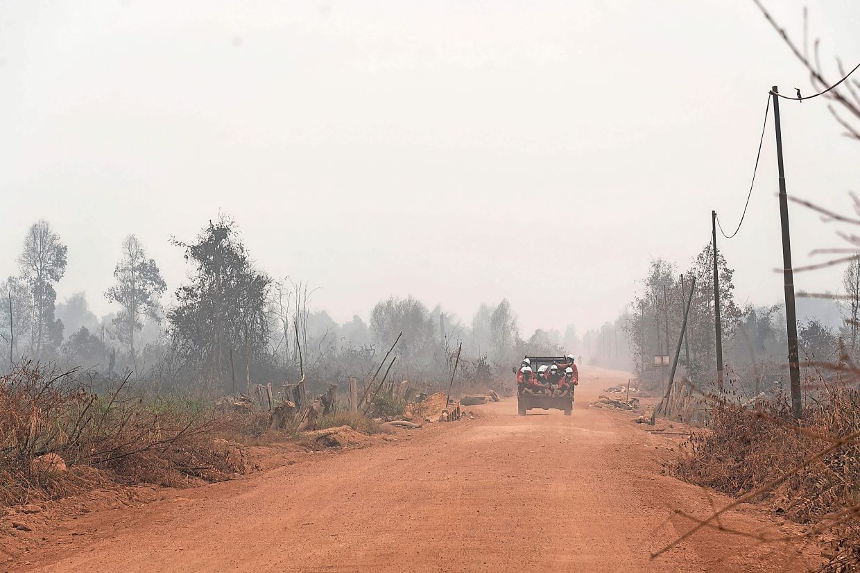 Members of the all-women The Power of Mama (TPoM) volunteer firefighting team ride on the flatbed of a truck along a dirt road toward the Benipis area in between Tanjungpura and Ulak Medang villages in Ketapang Regency, West Kalimantan. Indonesia has been battling fires in parts of Borneo and Sumatra, sending suffocating haze across the islands. —HERIBERTUS/AFP