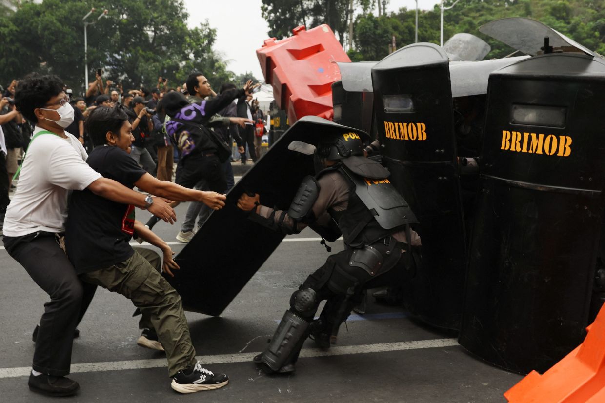 University students scuffle with a police officer carrying riot shield during a protest against Indonesian President Prabowo Subianto's policies and the government's handling of wildfires in Jakarta on Oct 28. - Reuters