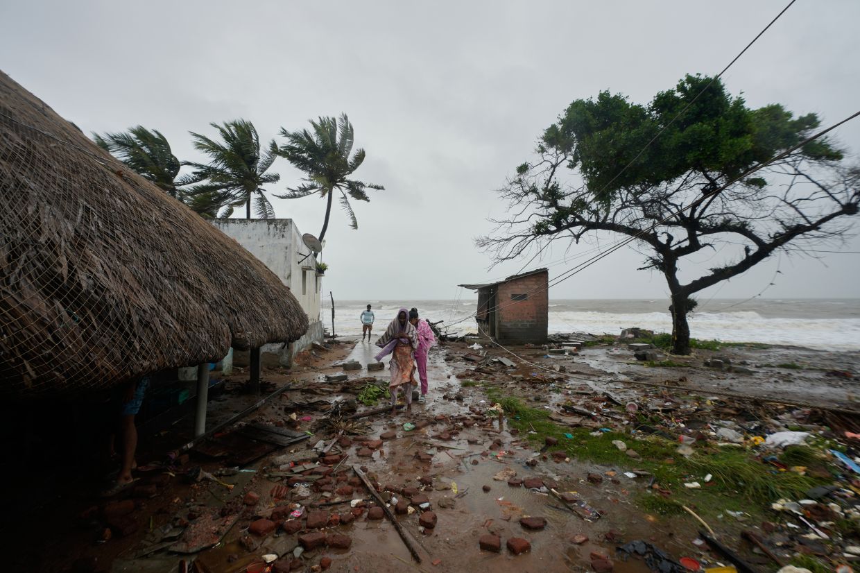 Members of a fishing family walking along the shore in Kakinada, India, as Cyclone Arnab made landfall along the Andhra Pradesh coast early on Oct 28. - AP