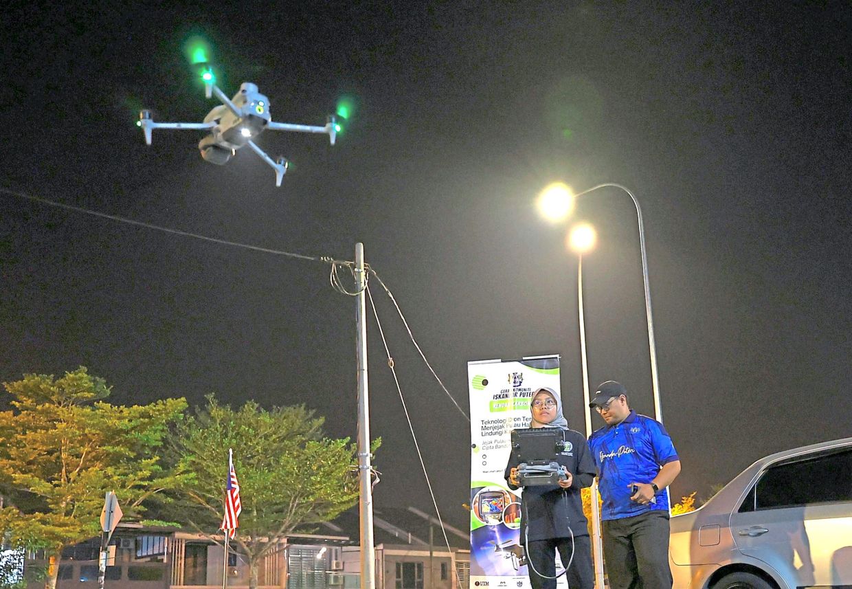 UTM Master of Philosophy (Geomatics Engineering) student Norfazirah Mohamed Fadil (left) operating a thermal imaging drone over Taman Pulai Indah night market in Iskandar Puteri to map heat emitted by the stalls.