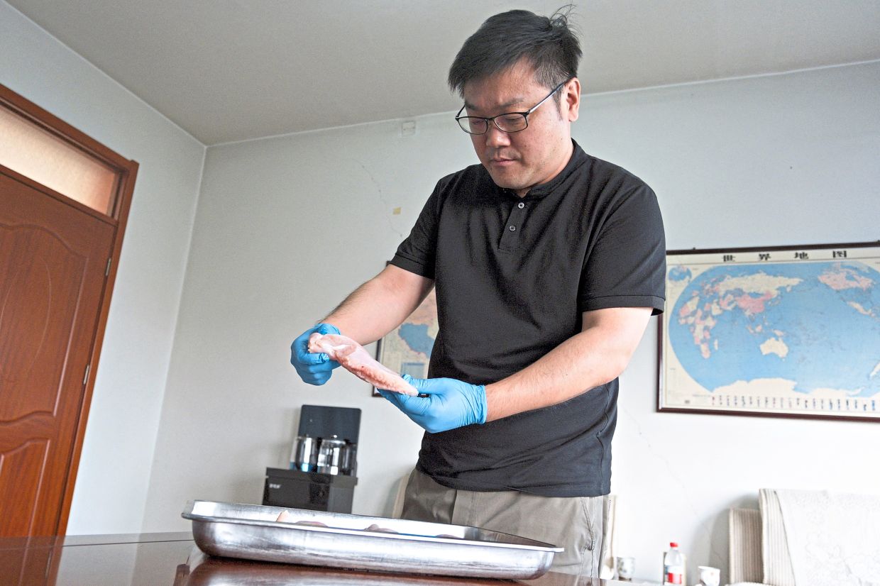 Dang, of poultry company Wintop Food Group, inspecting chicken breast meat as he speaks at his office in Tengzhou, Shandong province, China. — Reuters