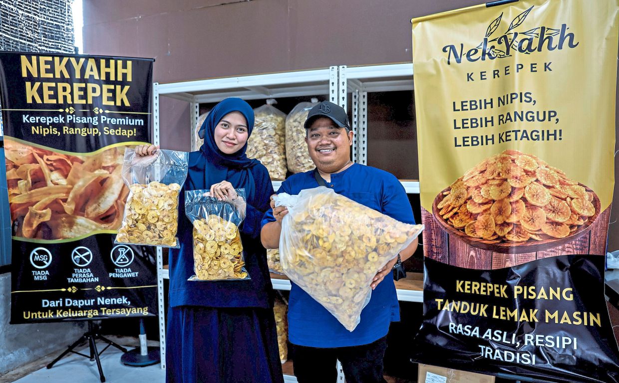Muhammad Akram and Siti Farhana holding bags of banana chips at their factory in Parit 6 Tebuk Pulai, Sabak Bernam.