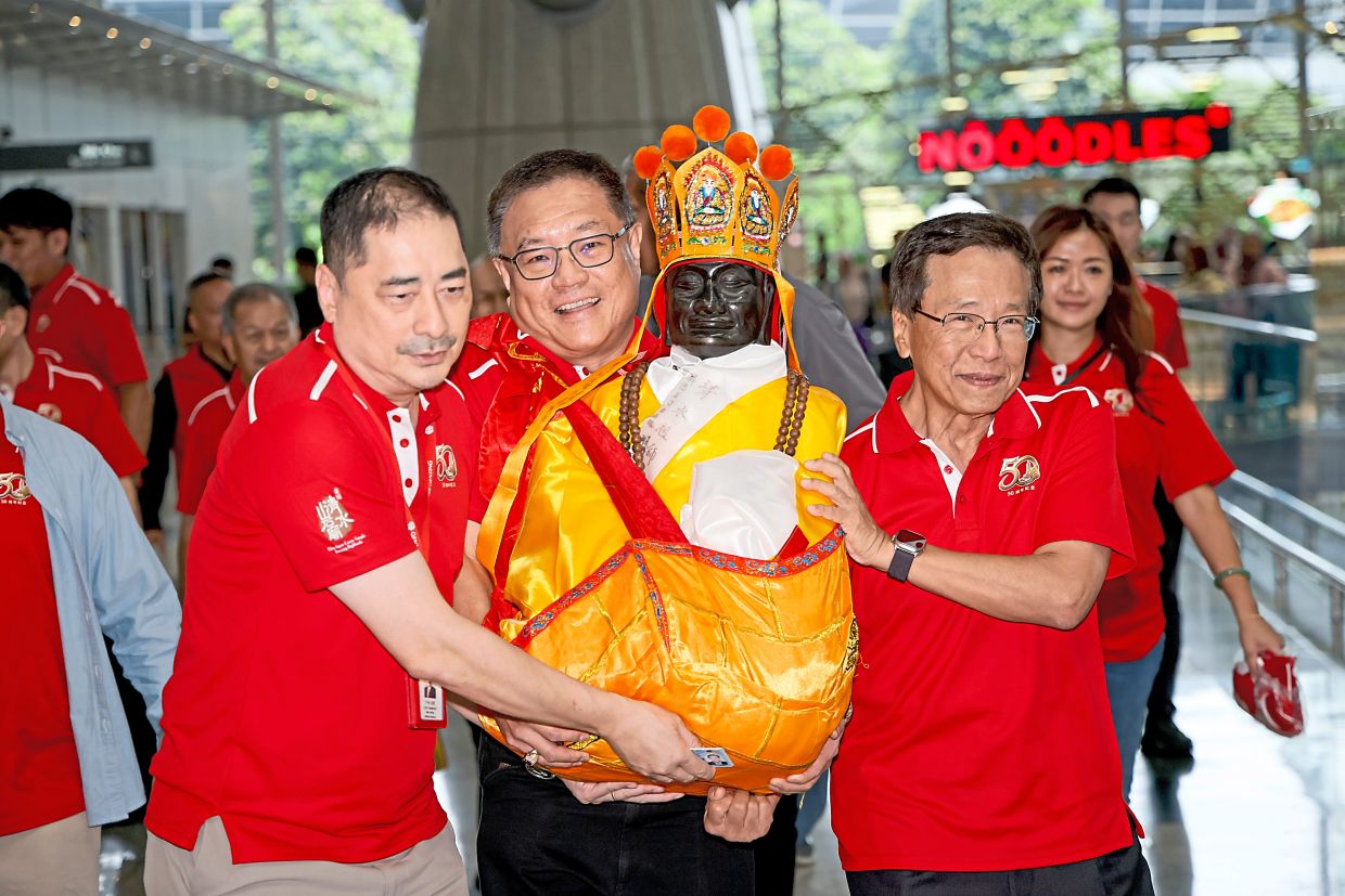 Lim (right) with (from left) Chin Swee Caves Temple Building Society general secretary Datuk Lee Thiam Kit and vice-chairman Datuk Seri Tan Kong Han carrying the deity statue.