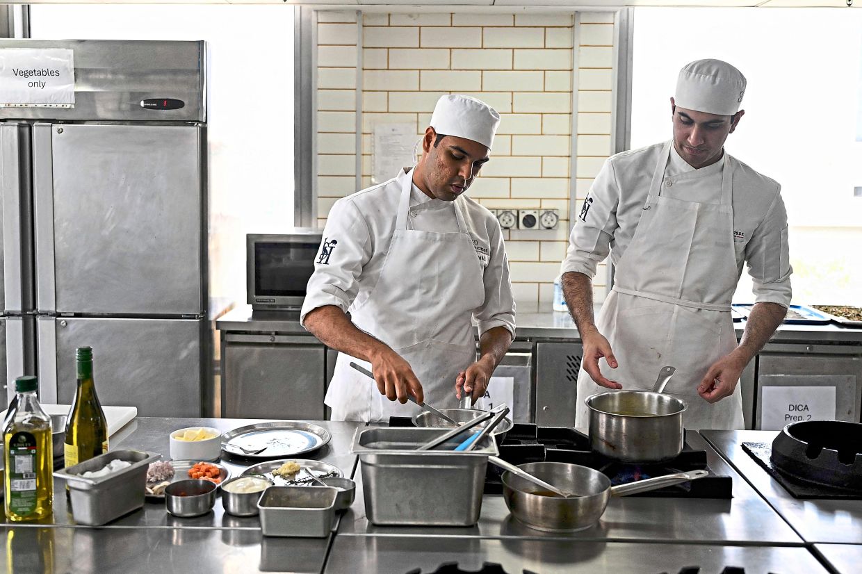 Behind the scenes: Student chefs working in a kitchen at Ecole Ducasse. — AFP