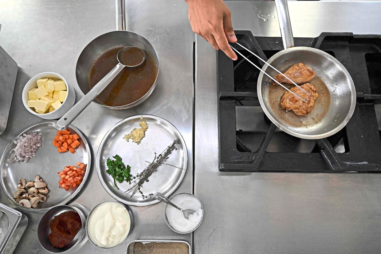Hands-on training: A student chef preparing the classic French dish ‘Poulet saute chasseur’ at the Ecole Ducasse. — AFP