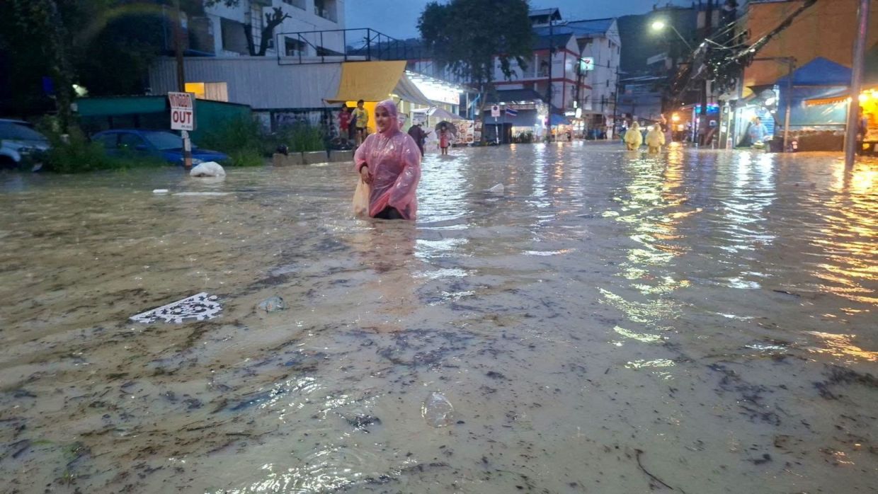 People wade through a flooded area in Patong, Kathu district, amid continuous heavy rainfall that triggered flash floods and mudslides in the area, in Phuket, Thailand October 28, 2026. - Photo: Phuket Provincial Public Relations Office/Handout via Reuters