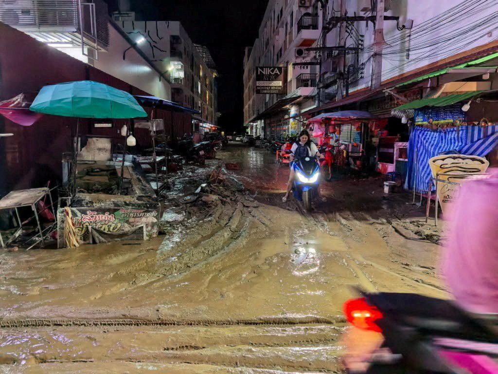 A woman rides a motorcycle along a mud-covered road in Patong, Kathu district, following continuous heavy rainfall that triggered flash floods and mudslides in the area, in Phuket, Thailand October 26, 2026. - Photo: Phuket Provincial Public Relations Office/Handout via Reuters