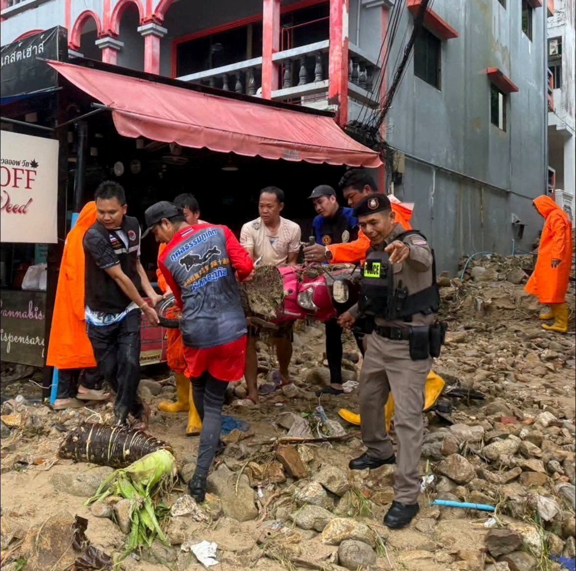 Rescue workers and a police officer help move a motorcycle through landslide debris in Patong, Kathu district, as authorities clear debris after heavy rain triggered flash floods and mudslides, in Phuket, Thailand Oct 26, 2026. - Photo: Phuket Provincial Public Relations Office/Handout via Reuters
