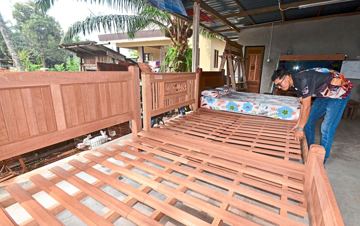 Muhammad Atifin inspecting one of his beds made from hardwood. Photos: Bernama 