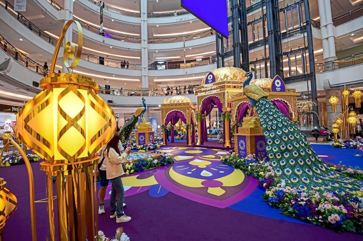 Two 3m-tall peacocks lead visitors toward a golden pavilion at Suria KLCC’s Centre Court.